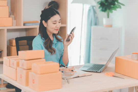 Young Asian woman holding a smartphone taking online orders from customers, SME business, online business, SME, work from home concept.
