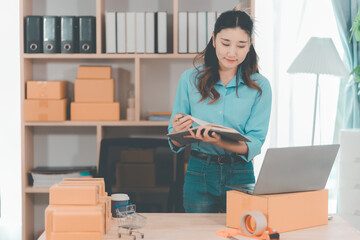 Small business startup. SME owner. Female entrepreneur checks online orders to prepare to pack...