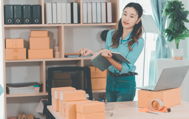 Small business startup. SME owner. Female entrepreneur checks online orders to prepare to pack...