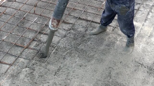Pouring ready-mixed concrete over steel reinforcement to create house. 