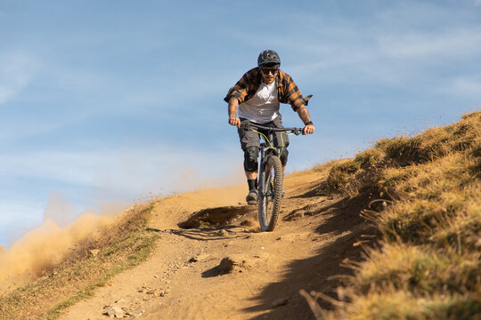 Mountain Biker Riding Down Steep Dirt Trail on Rocky Alpine Slope