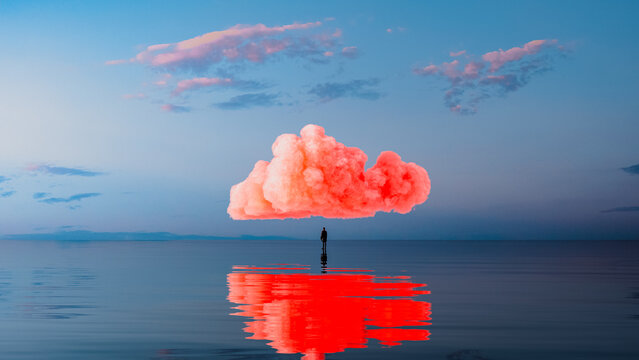 Silhouette of a man beneath a pink cloud over calm sea waters