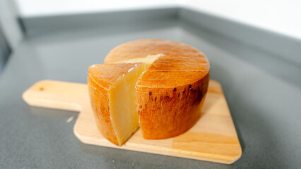 Rustic cheese wheel on wooden board in kitchen