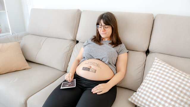 Expectant mother relaxing with baby bump on sofa
