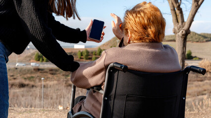 Grandmother and granddaughter outdoors with phone