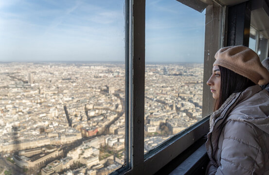 Woman gazing at Paris from Eiffel Tower in morning light
