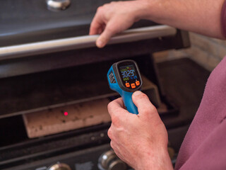 Man Measuring High Temperature of a Pizza Stone with a Digital Thermometer