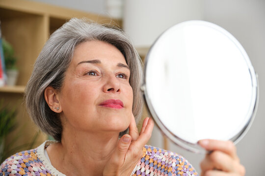 Smiling woman practicing self-care and optimism looking in mirror