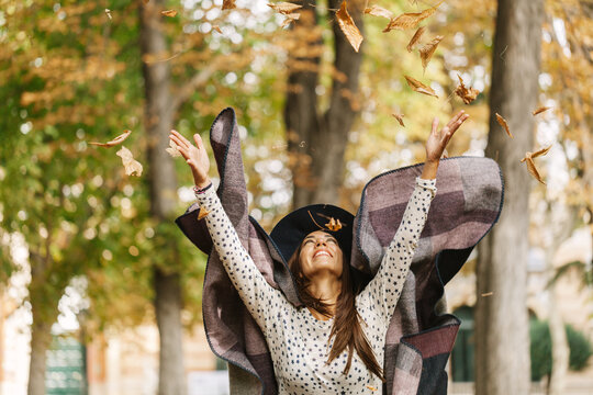 Joyful autumn day with a woman enjoying falling leaves