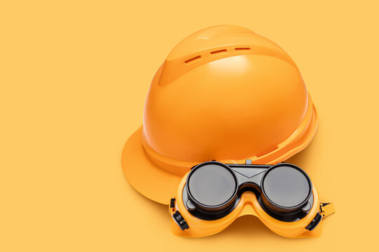 Hard hat and goggles on orange background