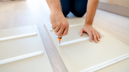 Man assembling furniture with a screwdriver