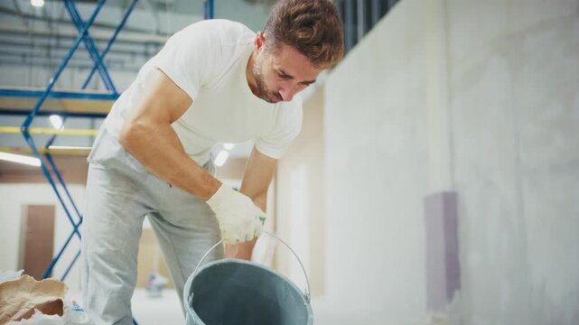 A dedicated worker transforms a space by preparing materials and using tools for construction in a modern building undergoing renovation and improvement.
