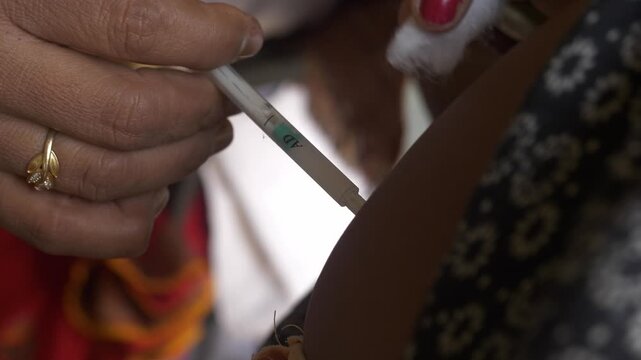 Social healthcare ASHA worker giving injection on arms of a pregnant woman during a maternal checkup in rural center, National Rural Health mission, Begusarai district, Bihar