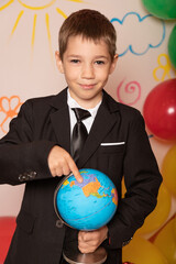 A schoolboy holds a globe in his hands. Geography lesson at school. Traveling around the world