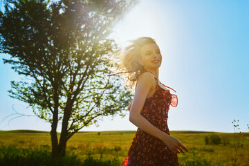 Joyful woman twirling in a sunlit summer meadow