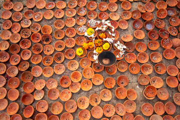 Arrangement of small terracotta diyas (lamps) and flower offerings, used for Hindu rituals and prayers, a cultural and religious display.