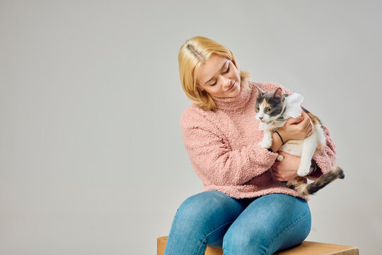 Woman holding a cat in a cozy studio setting