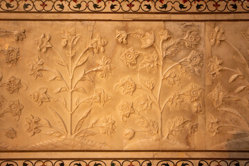 A detailed close-up of a marble wall with intricate floral bas-relief carvings. Perfect for architectural studies, historical documentation, and luxury interior design inspiration.