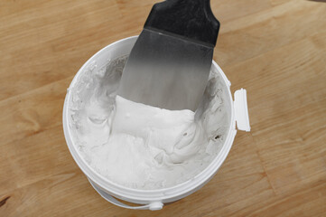 Ready-mixed thick repair putty in a bucket with a spatula