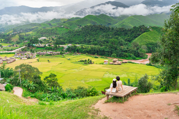 Young happy couple tourist enjoying and relaxing with beautiful landscape view rice paddy field while traveling at Nan, Thailand