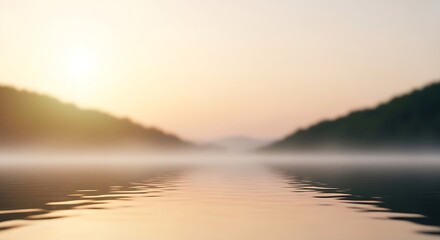 Fototapeta premium Misty sunrise over a calm lake, with hills shrouded in fog and golden light