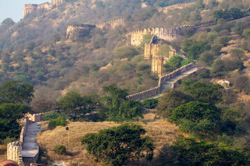 A winding ancient Indian fort wall ascends a hillside, an ideal visual for historical...
