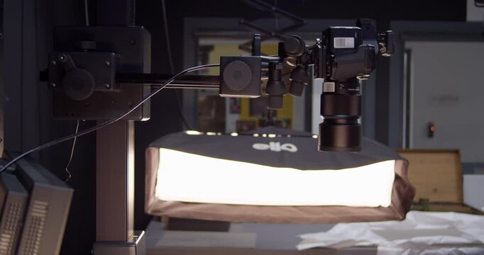 A high-end digital medium format camera travels vertically on a motorized repro stand column. This precise upward movement is part of a high-resolution scanning process for artwork and documents.