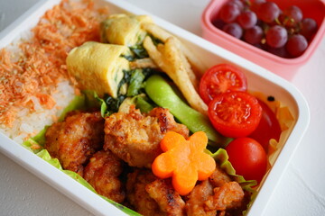 Japanese Lunch Box with Fried Chicken, Rolled Omelet, Salmon Flakes, Vegetables, and Grapes