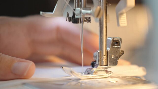 Woman using sewing machine to sew clothes. Close up of female hands, sewing machine needle and presser foot with thread