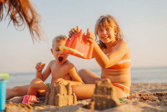Children building sandcastles on beach at sunset: summer vacation fun