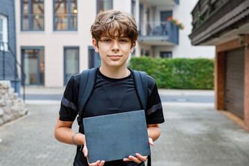 Teenage school boy with backpack holding sign chalk desk, empty, for copyspace for text standing...