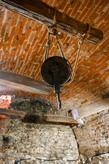 Old wooden pulley hangs from the ceiling in an ancient building, showcasing the historical construction techniques
