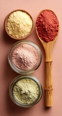Three bowls and a wooden spoon holding colorful powders
