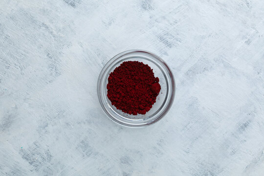 Azorubine or Carmoisine powder in glass bowl, top view. Red synthetic food dye. Food additive E122. Artificial coloring is commonly used in candies, soft drinks, jellies, and pharmaceutical products