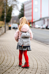Cute little preschool girl going to playschool. Healthy toddler child walking to nursery school and kindergarten. Happy child with backpack on the city street, outdoors.