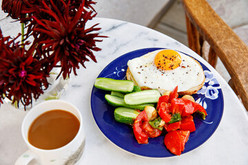 Healthy breakfast with fried egg, cucumber, fresh tomatoes and herbs. Nutritious morning meal with...