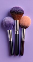 Three makeup brushes in varying shades of purple and peach,  set against a vibrant lavender background.  