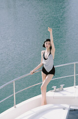 Young woman in stylish swimwear posing confidently on a yacht.
