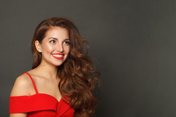 Fototapeta premium Joyful fashion model woman with shiny skin, wavy hairstyle and red lips makeup on black background