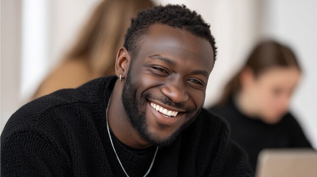 Smiling young African man in casual office, confident professional portrait, positive workplace and career success
