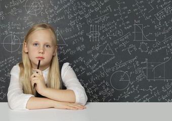 Clever child student sitting in classroom on school chalkboard background. Math education concept