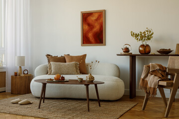 Warm-toned living room with beige sofa, textured cushions, wooden coffee table  and dried flowers...