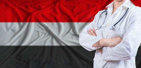 Doctor with crossed arms on Yemen flag. Yemeni health and care concept. Female doctor on Yemen flag