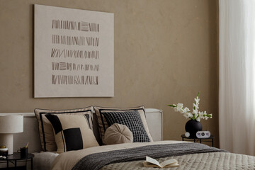 Contemporary bedroom interior with neutral bedding, black and beige pillows and white gladiolus in...