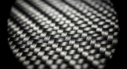 Close-up macro detail of a black carbon fiber surface with intricate woven texture and high-tech appearance.