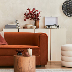Stylish interior of modern living room with retro design sofa, mock up poster frame, pouf and creative personal accessories. Hipster space. Template.