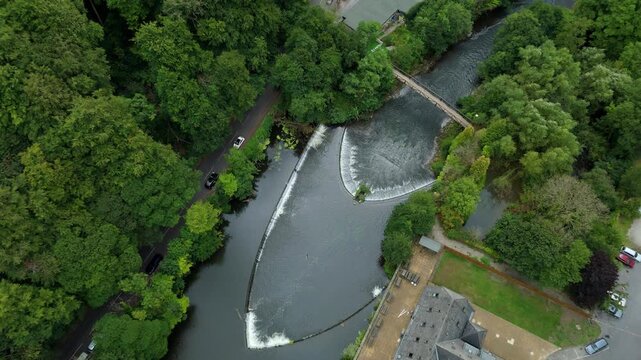 Top down aerial drone view of large bow shaped Weir on river Derwent, water control structure, Millbrook in Derbyshire Dales in England UK
