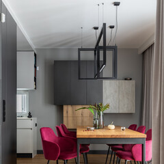 Elegant dining room interior design with velvet chairs, design wooden table, lamps and beautiful...
