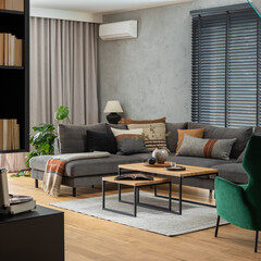 Stylish composition of living room interior with corner grey sofa, design furniture and minimalist personal accessories. Book shelf. Modern home decor. Template.