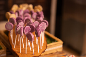 Purple lollipops displayed on wooden tray at dessert table